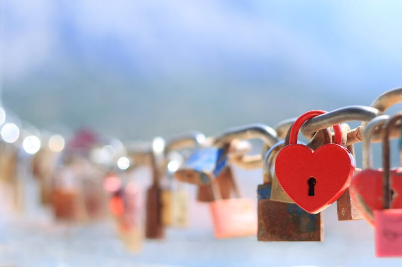 Close-up of love lock with a red heart shaped padlock hanging on chain with the sea in the background. Love Lock Bridge in Amsterdam. 