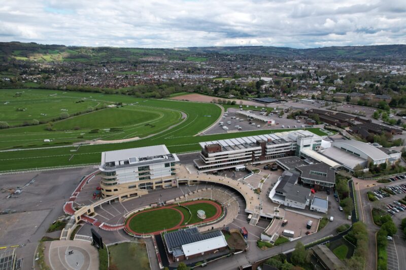 Aerial shot of Cheltenham Racecourse with an oval of grass surroudned by stands and other buildings