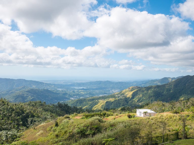 view of a green mountain landscape on a sunny day with a blue sky filled with fluffy white clouds