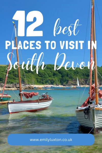 12 Best Places to Visit in South Devon, written in white text on top of a photo showing white wooden sailboats in a river  near Salcombe on a sunny day with a green forest on the distant bank. 