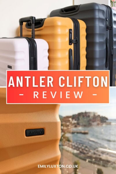 Antler Clifton Review, written in white text on an orange box, above is a photo of 3 hardshell suitcases in a row of ascending size, below is a photo of a yellow hardshell suitcase with a blurred view of Antalya behind. 