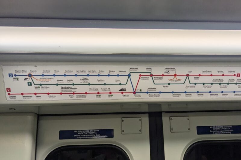 close up of a white recangular sign with a map of Athens metro made up of three coloured lines