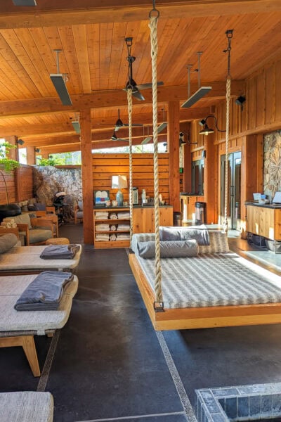 interior of a spa with pine wood walls and cielings with a double bed hanging from the cieling on ropes. There is a light grey mattress on the bed. Spa at Rush Creek Lodge Tuolumne County California