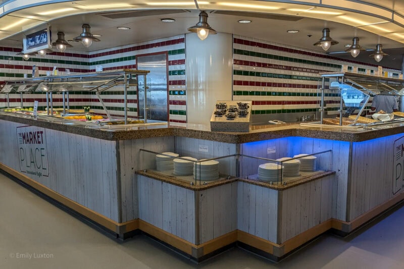 Long counter at a buffet restaurant with red white and green striped tiling on the wall behind.