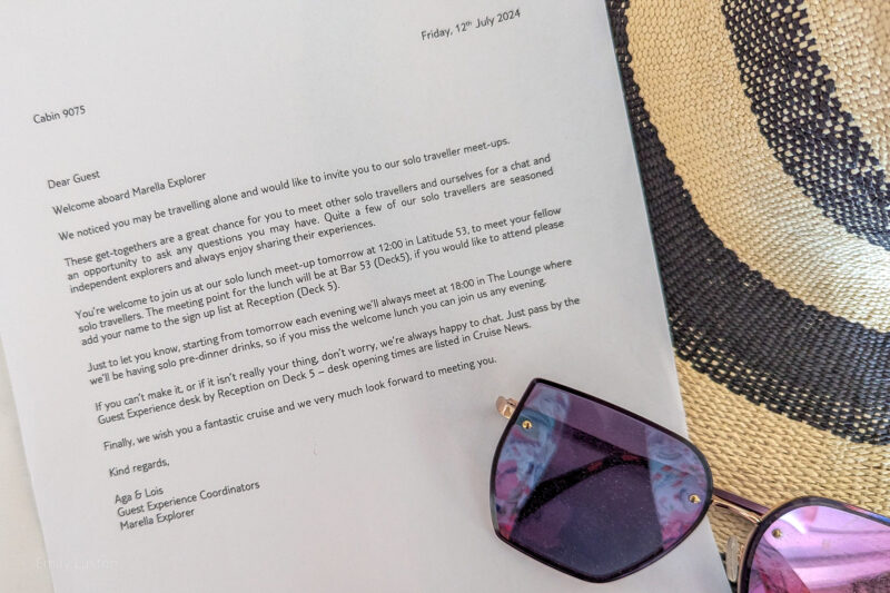 Close up of a letter with printed text on white paper next to a pair of purple sunglasses. The text reads: Dear Guest Welcome aboard Marella Explorer We noticed you may be travelling alone and would like to invite you to our solo traveller meet-ups. These get-togethers are a great chance for you to meet other solo travellers and ourselves for a chat and an opportunity to ask any questions you may have. Quite a few of our solo travellers are seasoned independent explorers and always enjoy sharing their experiences. You're welcome to join us at our solo lunch meet-up tomorrow at 12:00 in Latitude 53, to meet your fellow solo travellers. The meeting point for the lunch will be at Bar 53 (Deck5), if you would like to attend please add your name to the sign up list at Reception (Deck 5). Just to let you know, starting from tomorrow each evening we'll always meet at 18:00 in The Lounge where we'll be having solo pre-dinner drinks, so if you miss the welcome lunch you can join us any evening. If you can't make it, or if it isn't really your thing, don't worry, we're always happy to chat. Just pass by the Guest Experience desk by Reception on Deck 5 - desk opening times are listed in Cruise News. Finally, we wish you a fantastic cruise and we very much look forward to meeting you. Kind regards, Aga & Lois Guest Experience Coordinators