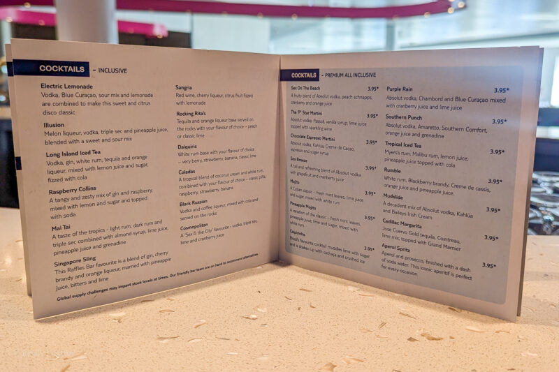 close up of a white 2 page menu with blue text listing different cocktails