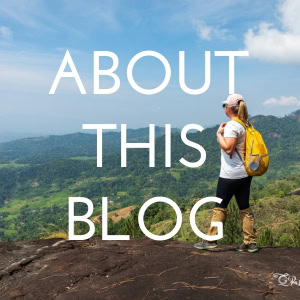 Button - the text reads About This Blog in white, behind is a photo of emily wearing white t shirt and black leggings with a yellow backpack standing on the edge of a cliff with a view of a lush green landscape beyond. 