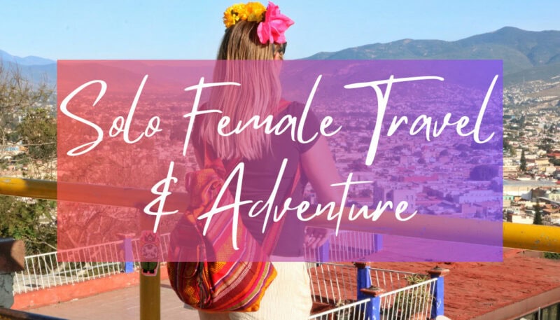 Solo Female Travel & Adventure - written in white text over a photo of british blogger Emily Luxton. She is facing away from the camera with a view of Oaxaca city in front of her. She is wearing white shorts and a black t-shir with an orange cloth backpack on and a pink and yellow flower crown on top of her head. 