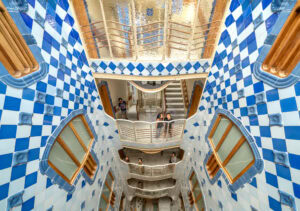 looking down from the 2nd floor of an interior courtyard where all the walls are covered in blue and white diamond shaped tiles