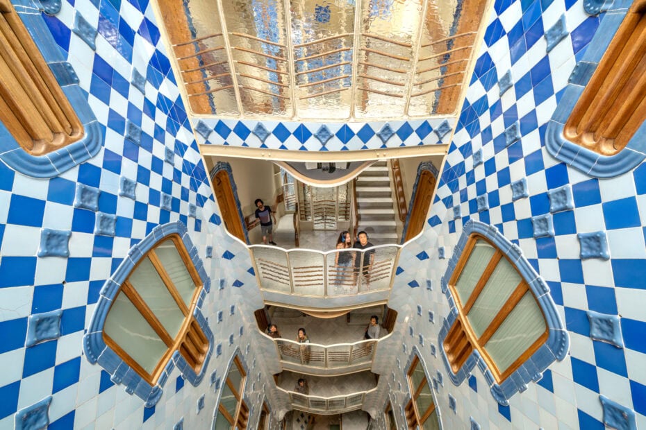 looking down from the 2nd floor of an interior courtyard where all the walls are covered in blue and white diamond shaped tiles