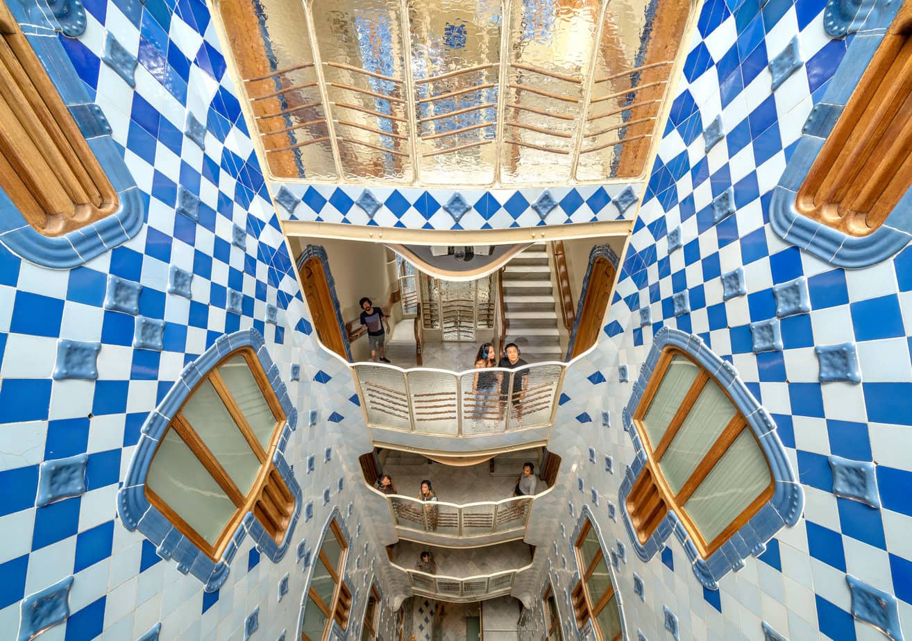 looking down from the 2nd floor of an interior courtyard where all the walls are covered in blue and white diamond shaped tiles