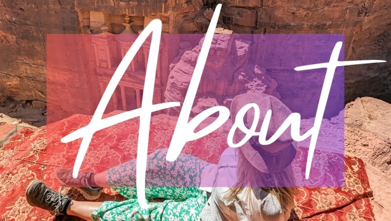 About written in white writing on a pink opague box, on top of a photo of British solo female travel blogger Emily Luxton. She is sitting on a cliff edge with a view of the Treasury at Petra behind her, and she is wearing green trousers with a white shirt and beige straw sunhat. 