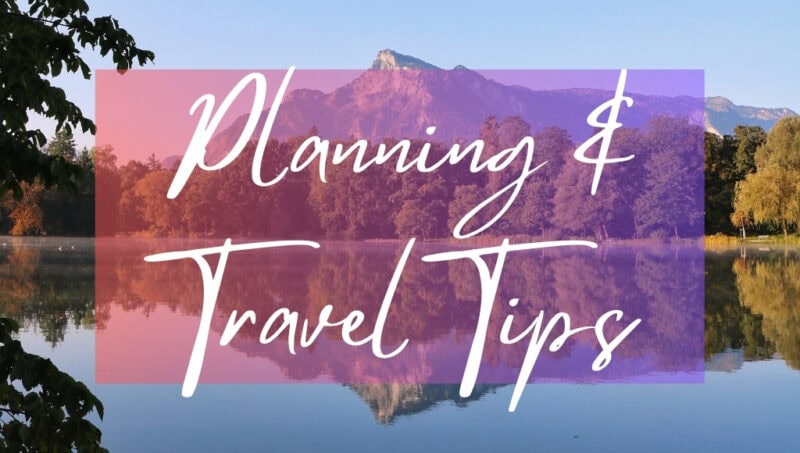 Planning and Travel Tips written in white text over an opaque pink box on top of a photo of a mountain surrounded by forest perfectly reflected in a large blue lake with very still water. It is a very sunny day with clear blue sky overhead. 