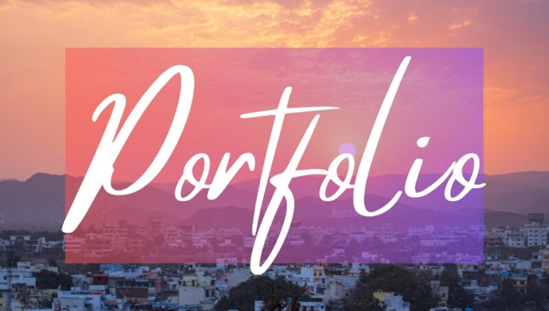 Portfolio written in white text over an opaque pink box on top of a photo of a sunset above a city skyline with the sky coloured orange