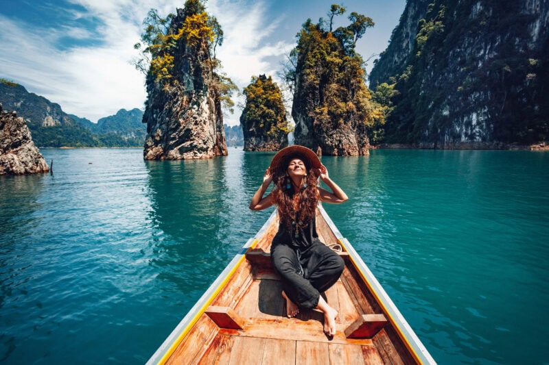 happy young woman tourist in asian hat on the boat at lake